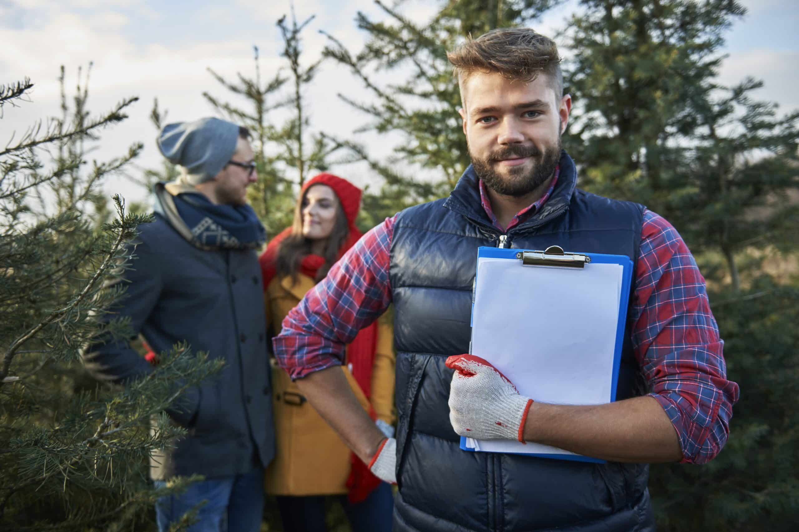 a man holding a clipboard in a tree farm.